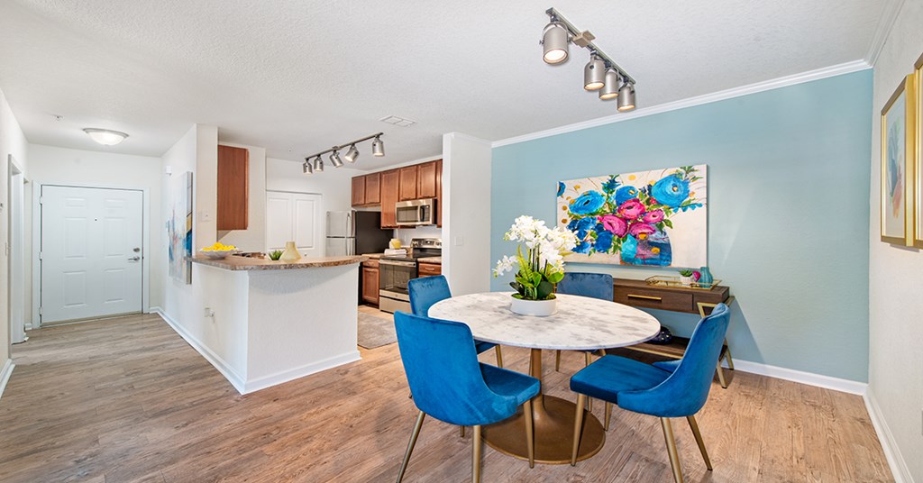 A kitchen with a white counter and blue chairs.