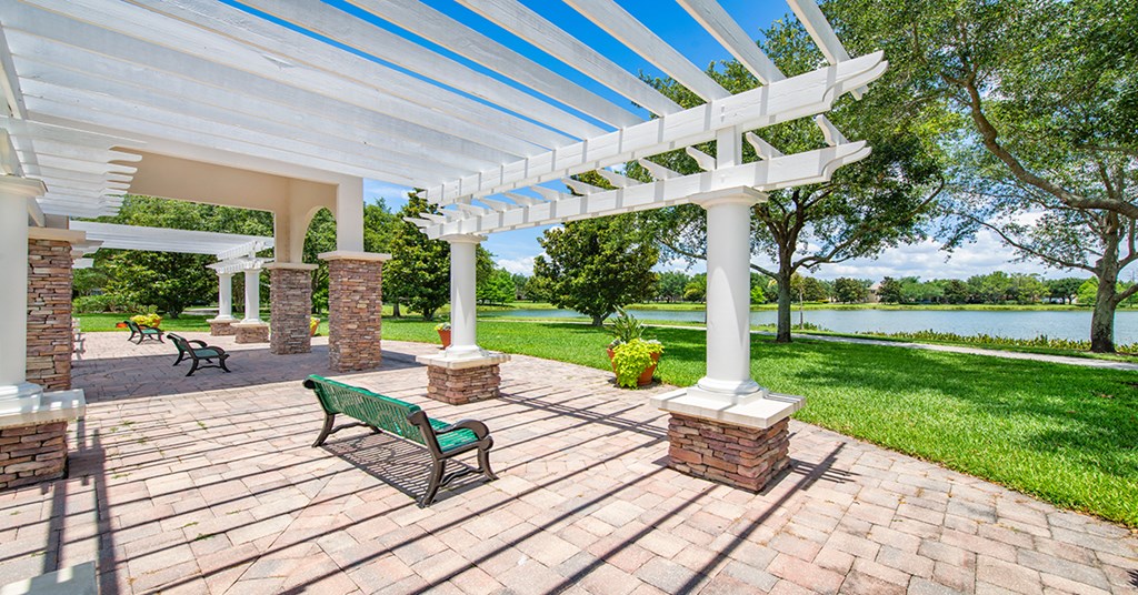 A white pergola with a green bench under it.