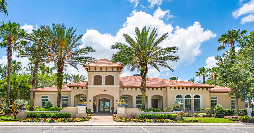 A building with a red roof and palm trees in front.