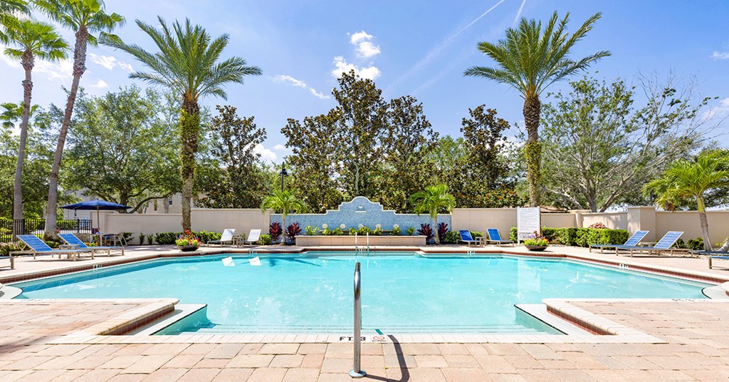 A large swimming pool surrounded by palm trees and lounge chairs.