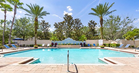 A large swimming pool surrounded by palm trees and lounge chairs.