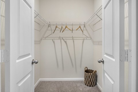 A white closet with a basket on the floor.