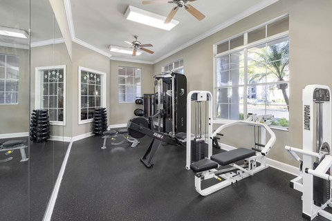 A well-equipped gym with a variety of machines and a ceiling fan.