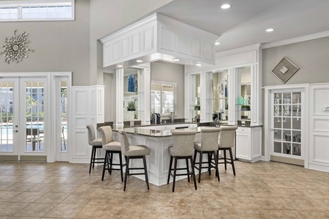A kitchen with a bar area and white cabinets.