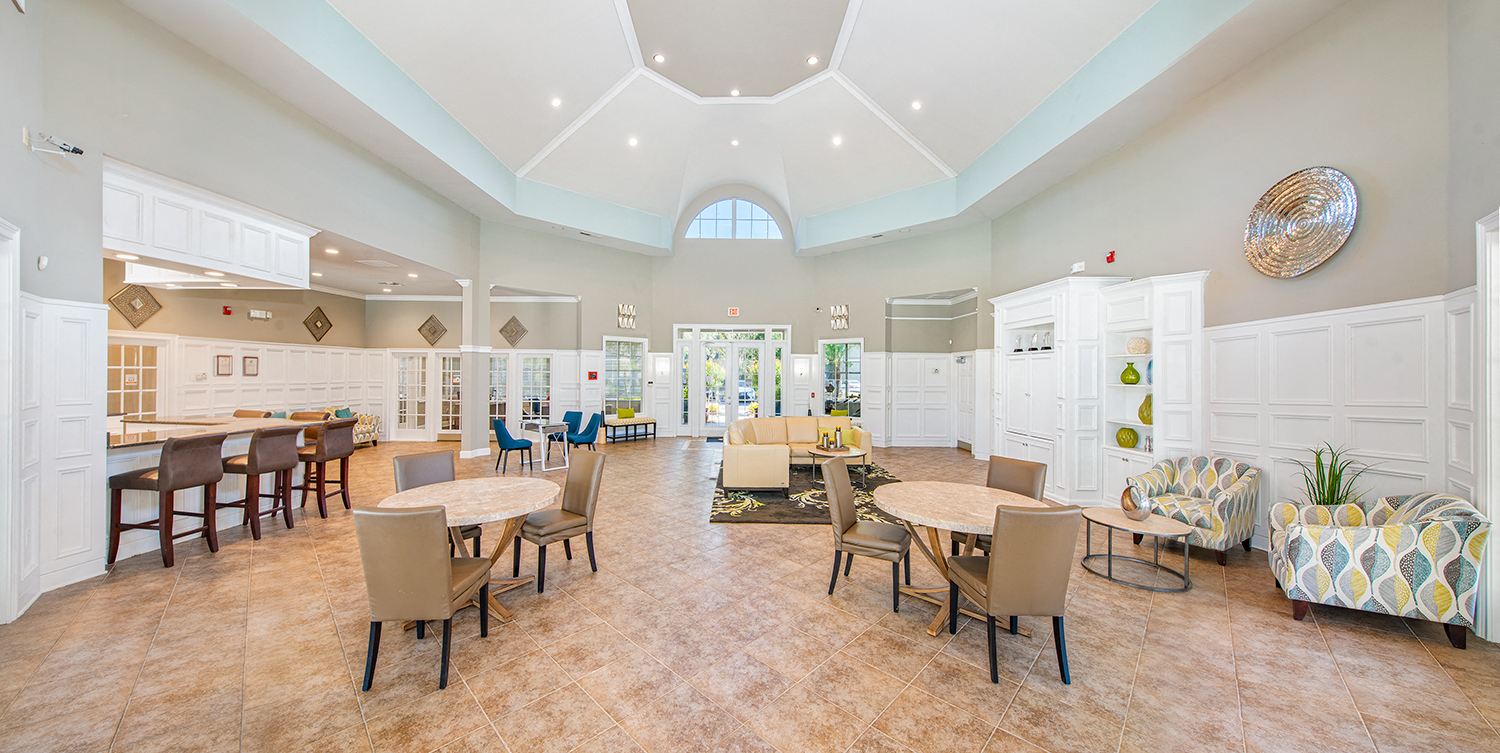 a community room with tables and chairs and a kitchen