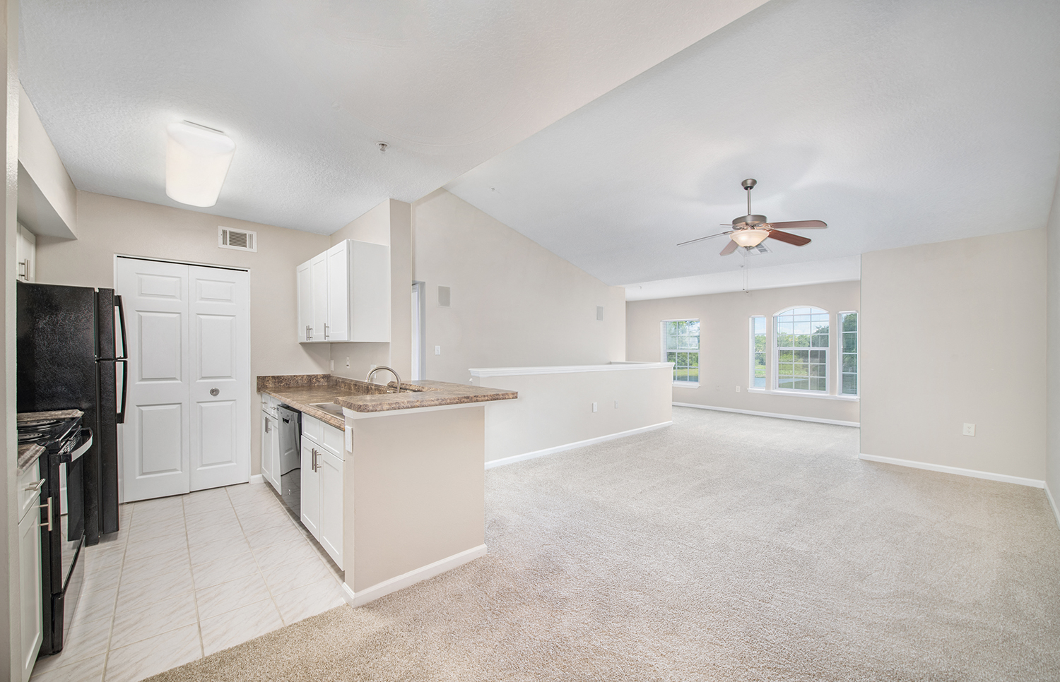 an empty kitchen and living room with a ceiling fan