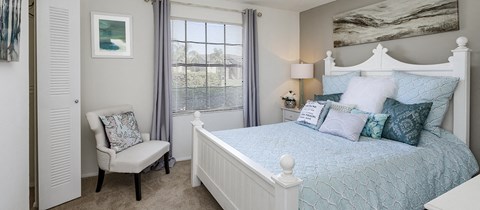 a bedroom with a bed and a chair and a window