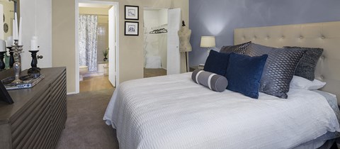 a bedroom with a bed and a dresser and a bathroom