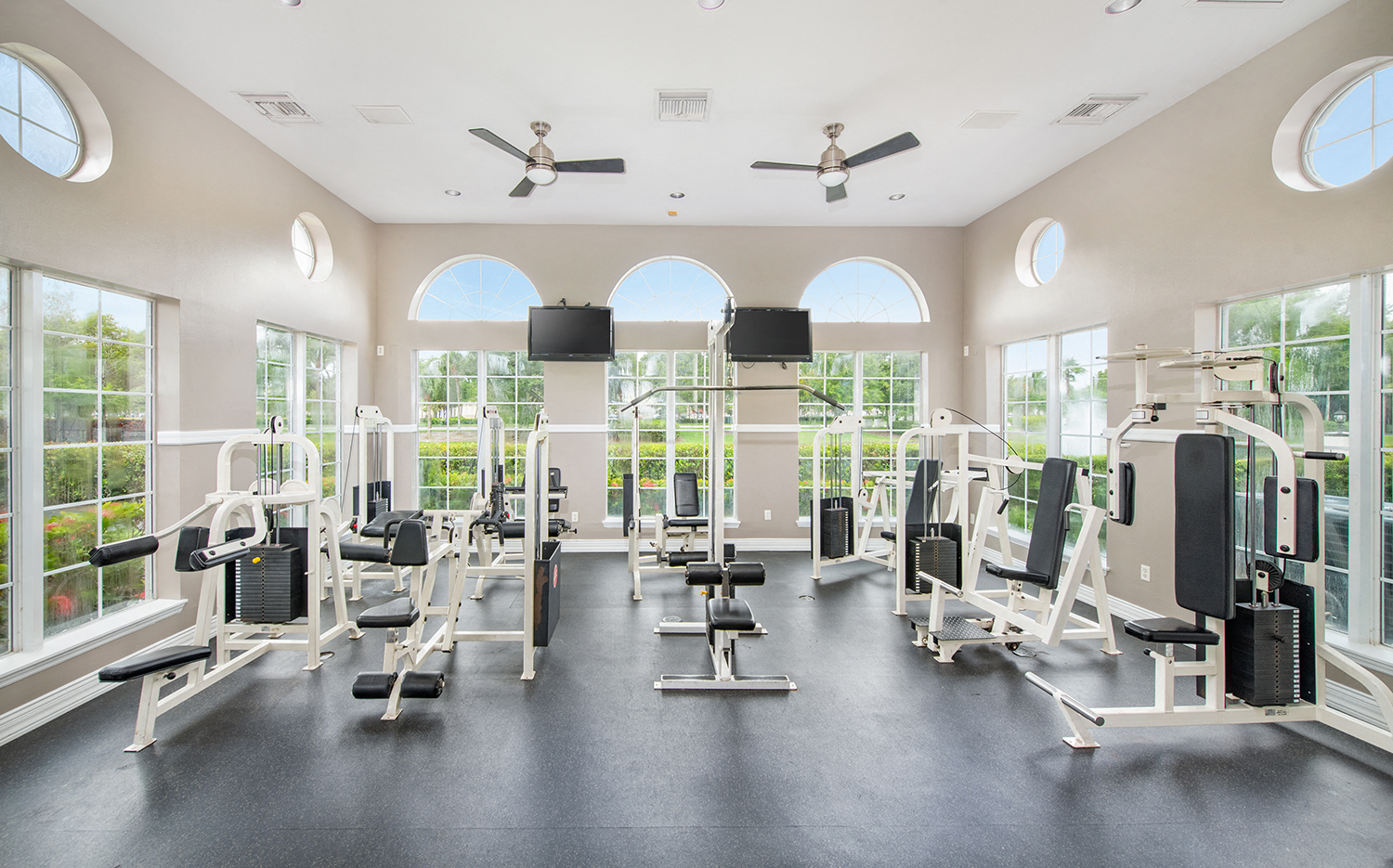 a gym with a large amount of exercise equipment and windows