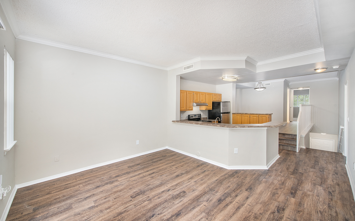 an empty living room and kitchen with wood flooring