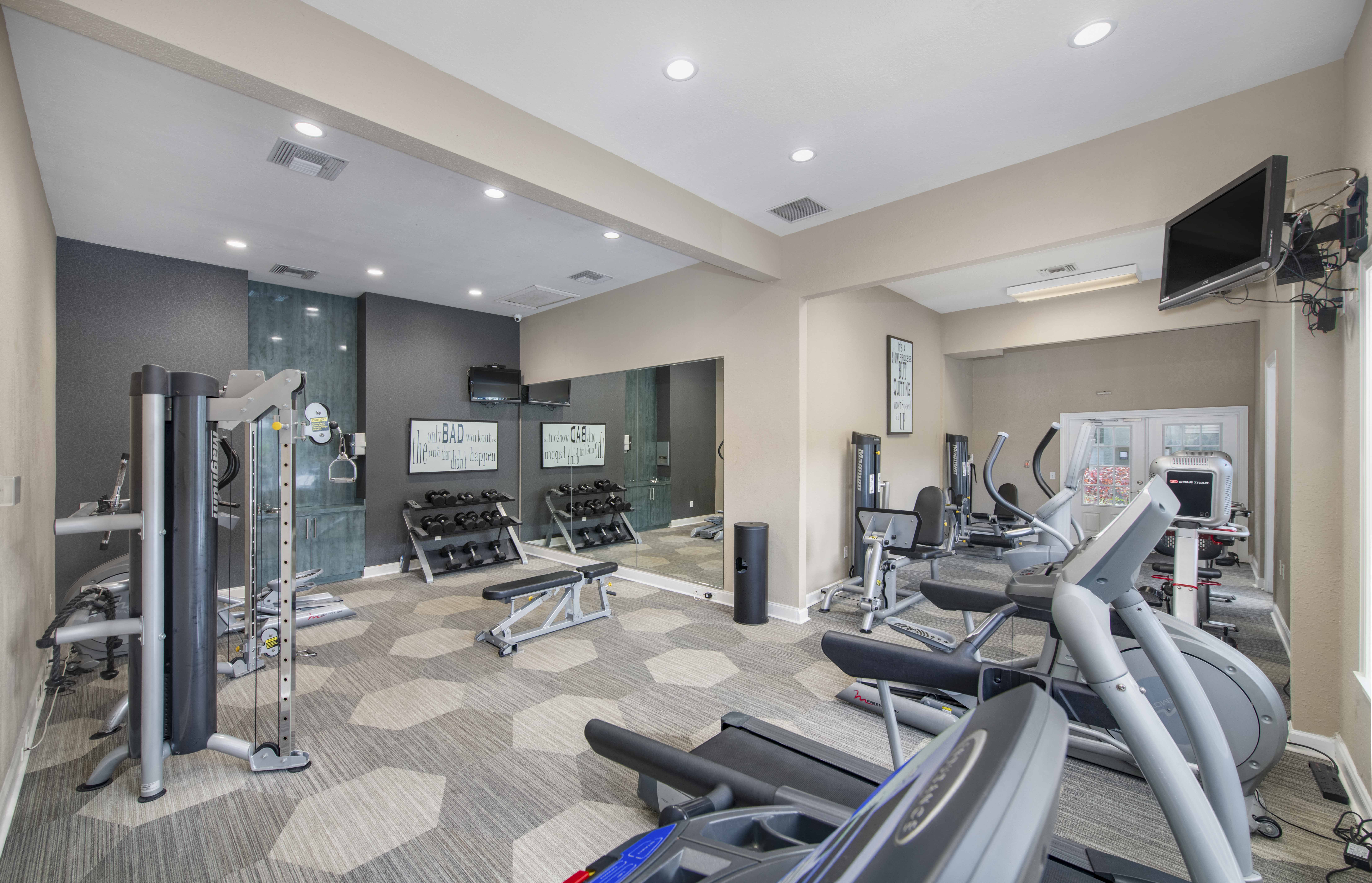 a gym with exercise machines and a tv on the wall