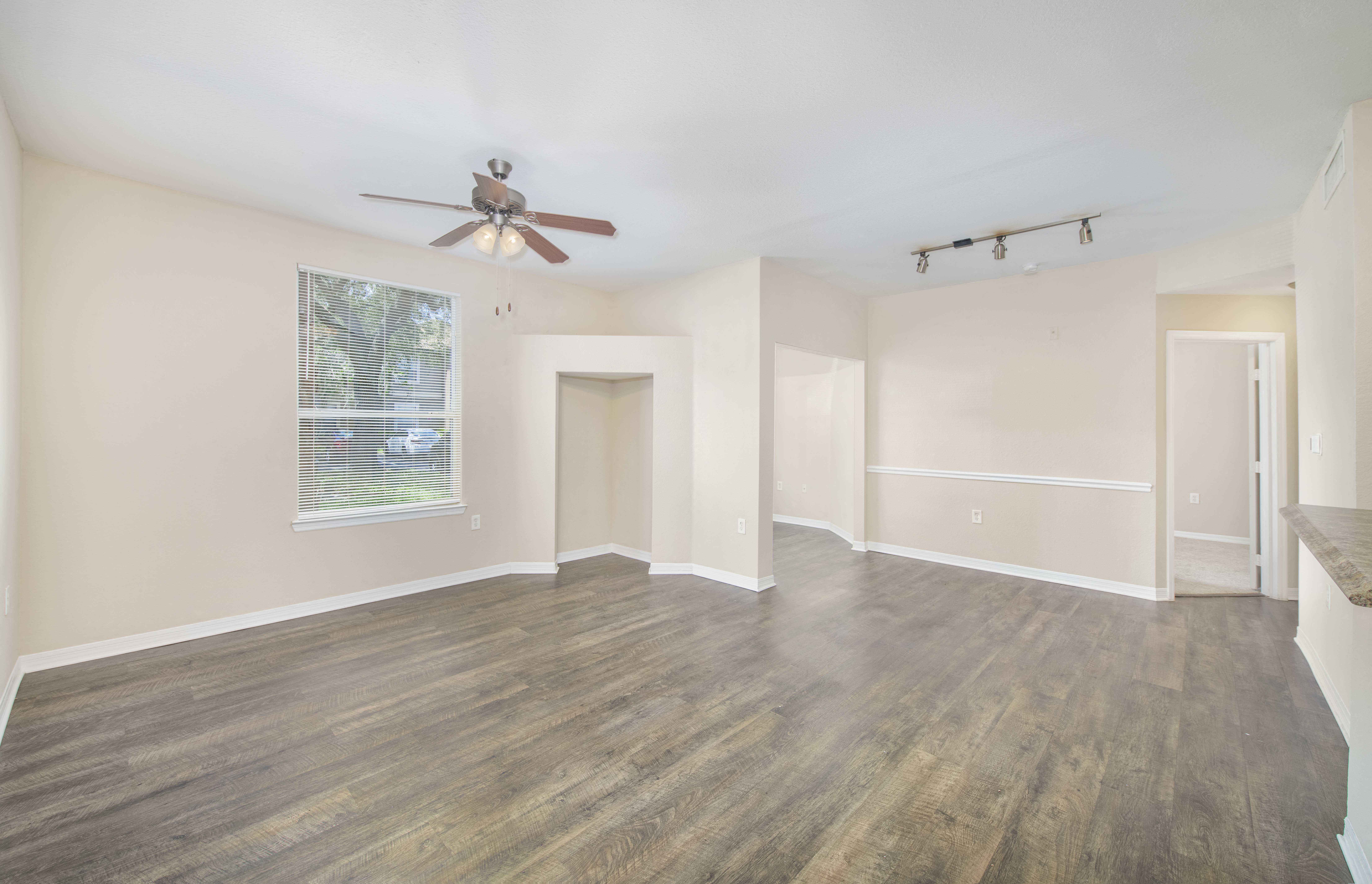 an empty living room with a ceiling fan and a window