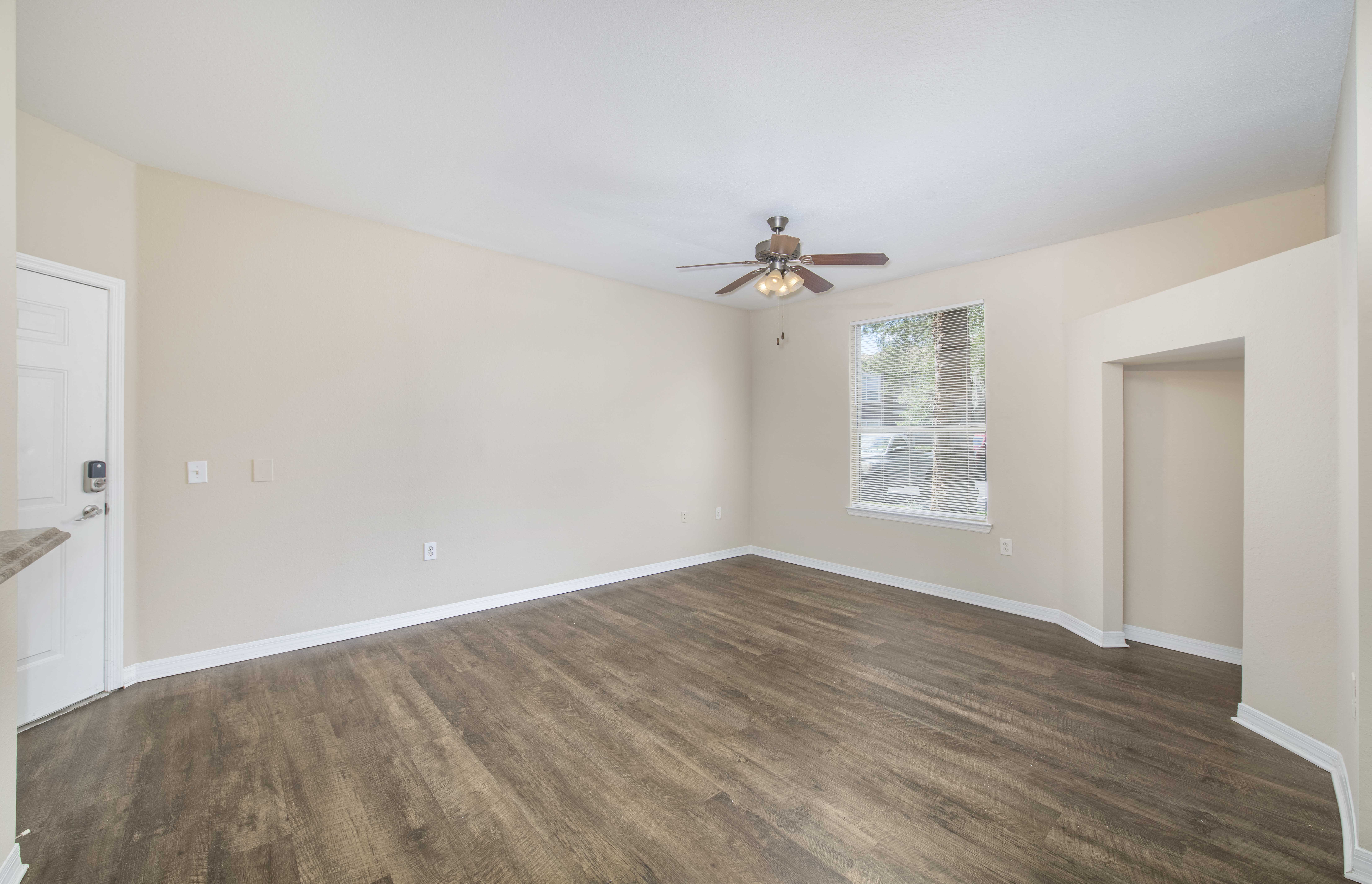 an empty living room with a ceiling fan and a window