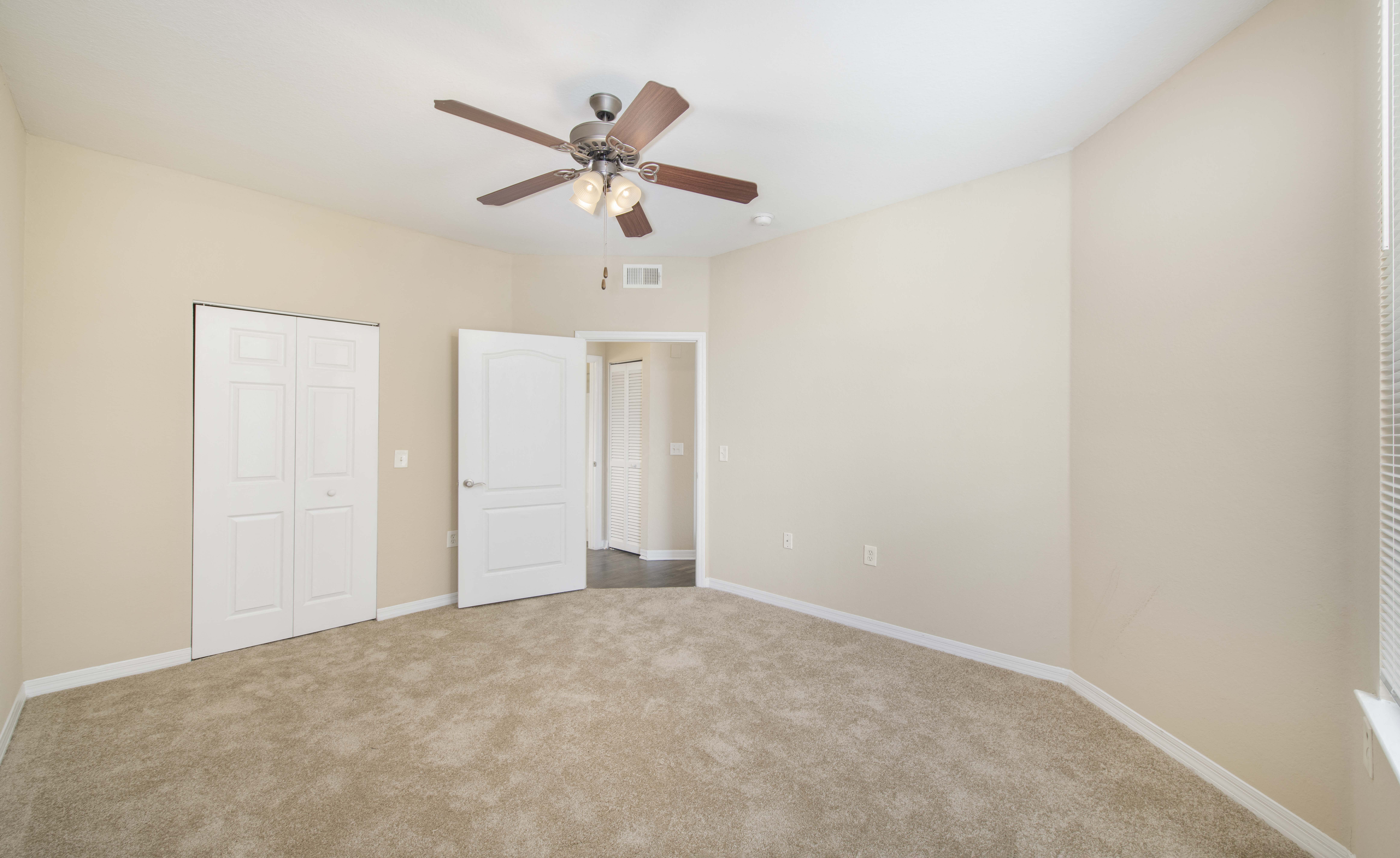 an empty living room with a ceiling fan and a closet