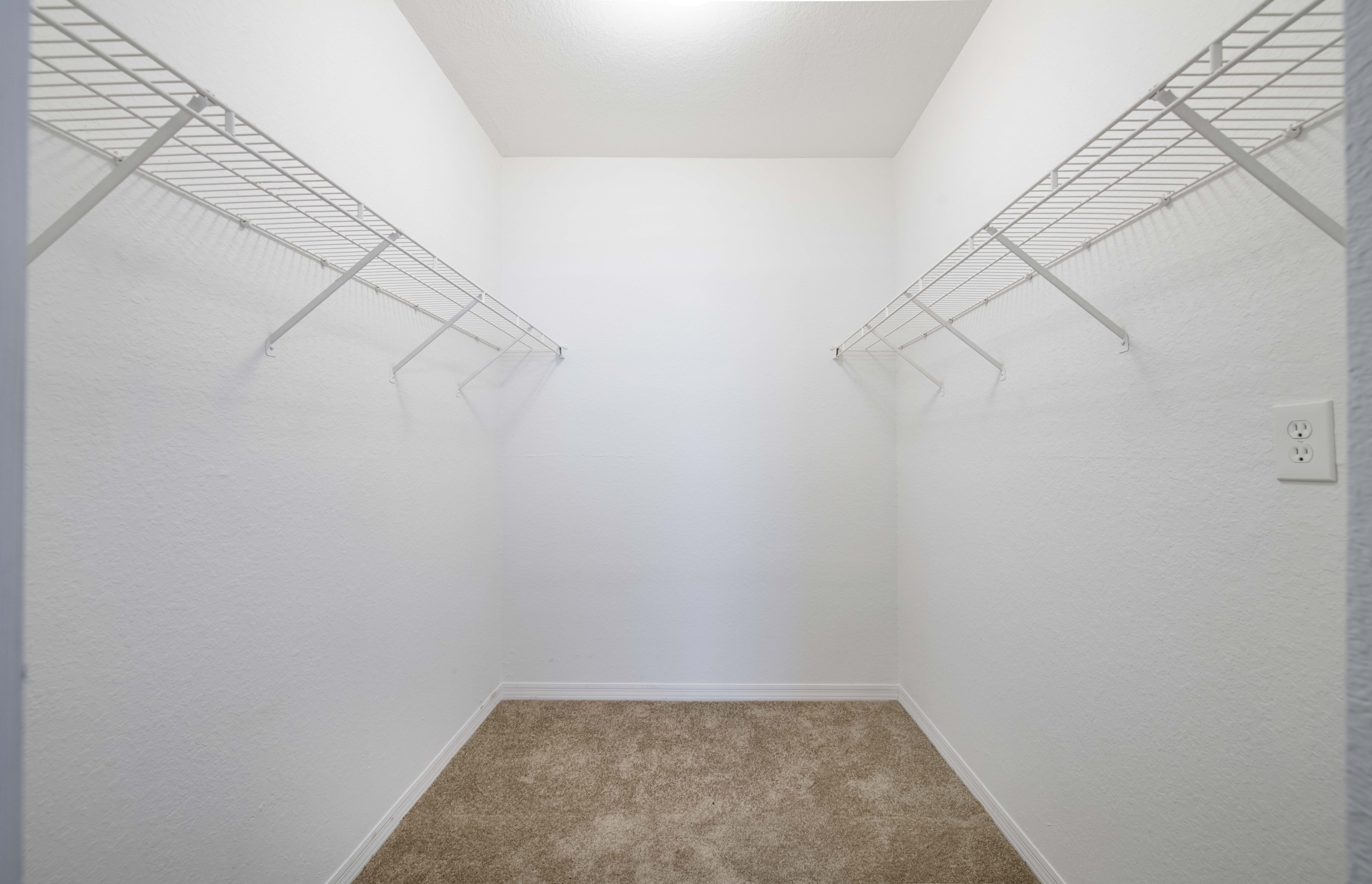 a spacious closet in a small room with white walls and carpet