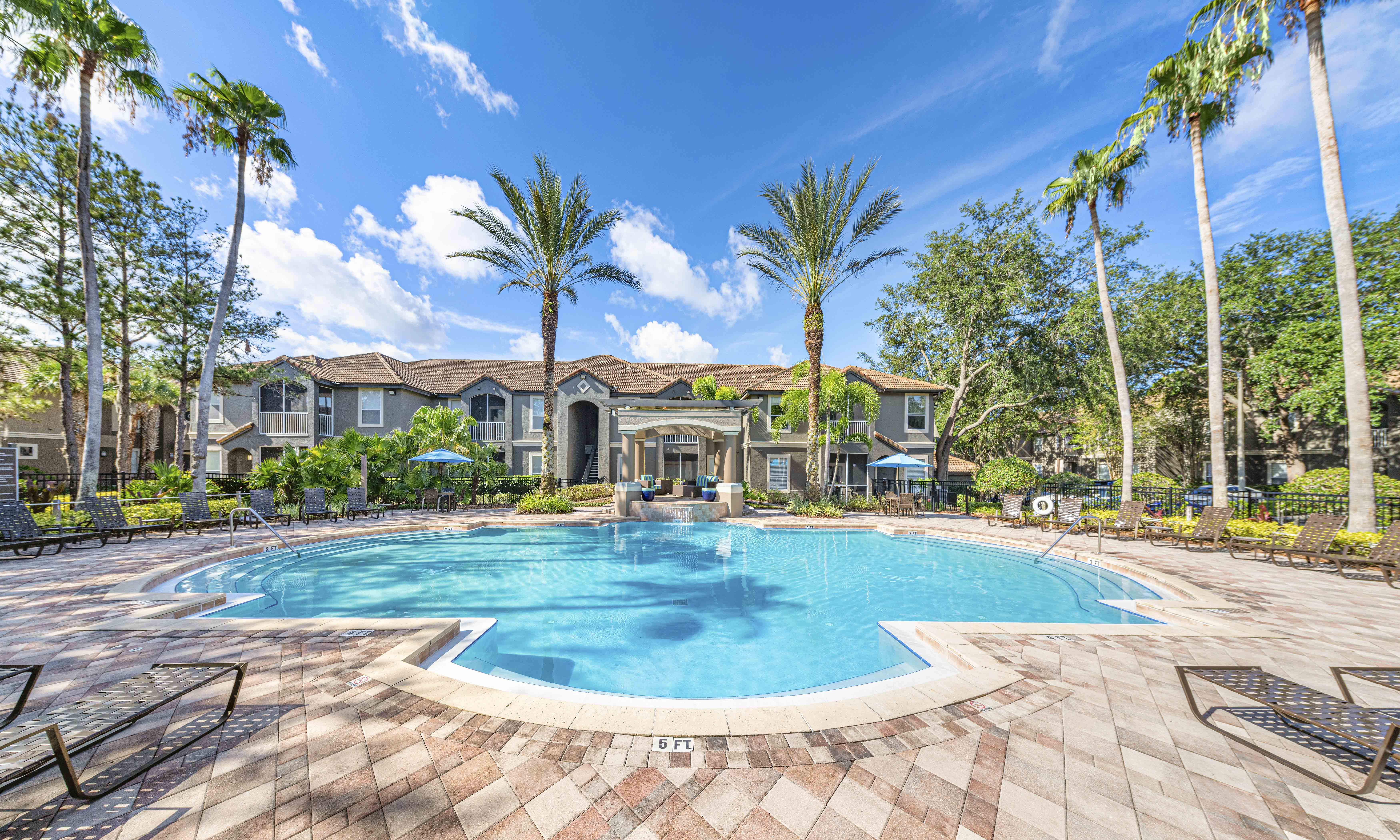 a large swimming pool with palm trees and a house in the background