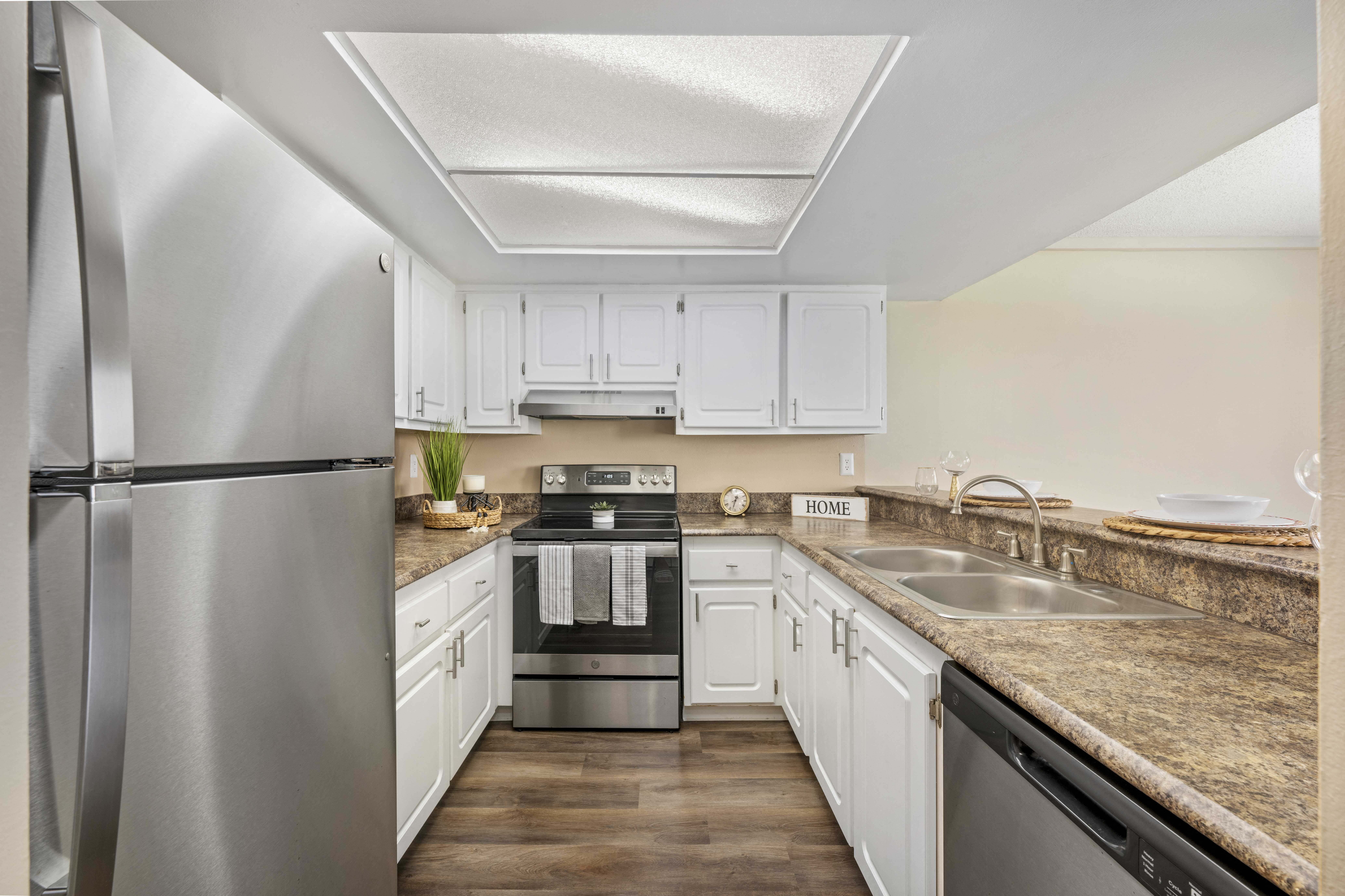 a kitchen with white cabinets and granite counter tops and stainless steel appliances