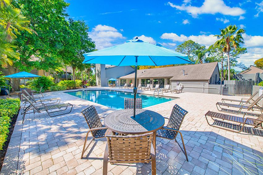 a swimming pool with patio furniture and an umbrella
