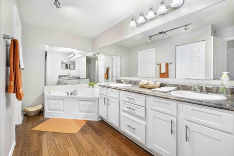 A bathroom with white cabinets and a wooden floor.