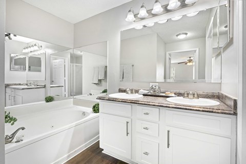 A white bathroom with a tub, sink, and mirror.