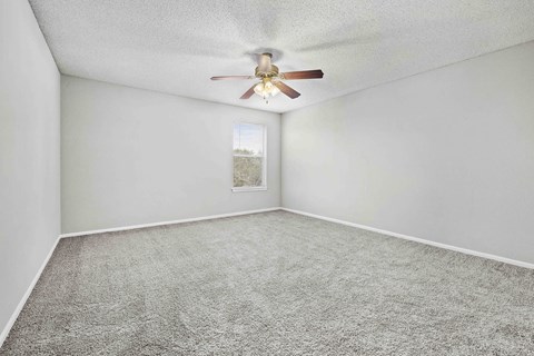 A room with a ceiling fan and carpeted floor.