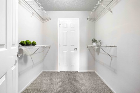 A white door is in the middle of a hallway with shelves on either side.