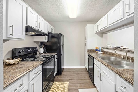 A kitchen with black appliances and white cabinets.