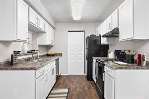 A kitchen with white cabinets and a black refrigerator.