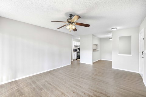 A room with a ceiling fan and wooden flooring.