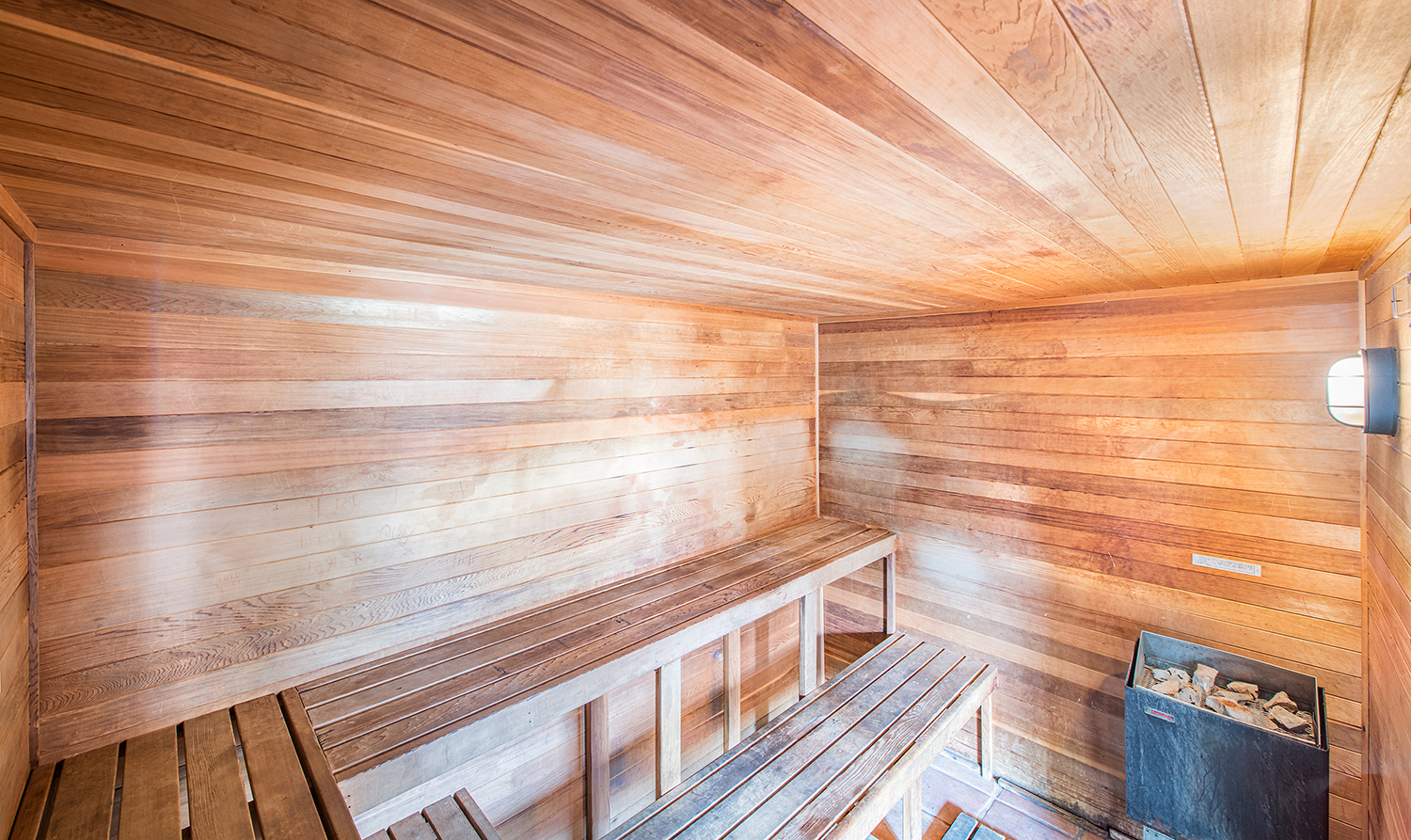 a wooden sauna with wooden benches and a bucket of rocks