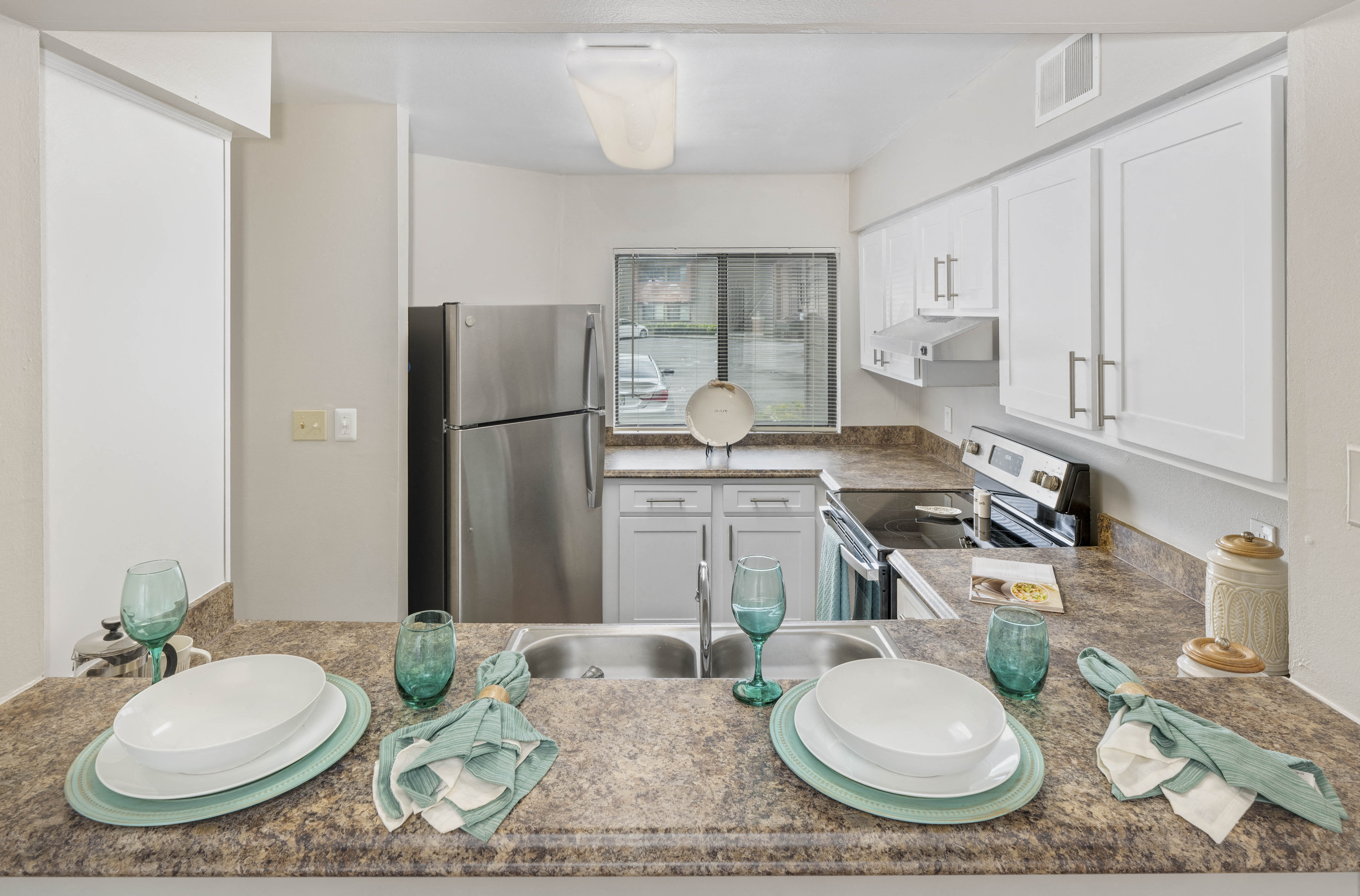a kitchen with stainless steel appliances and a table with plates and glasses