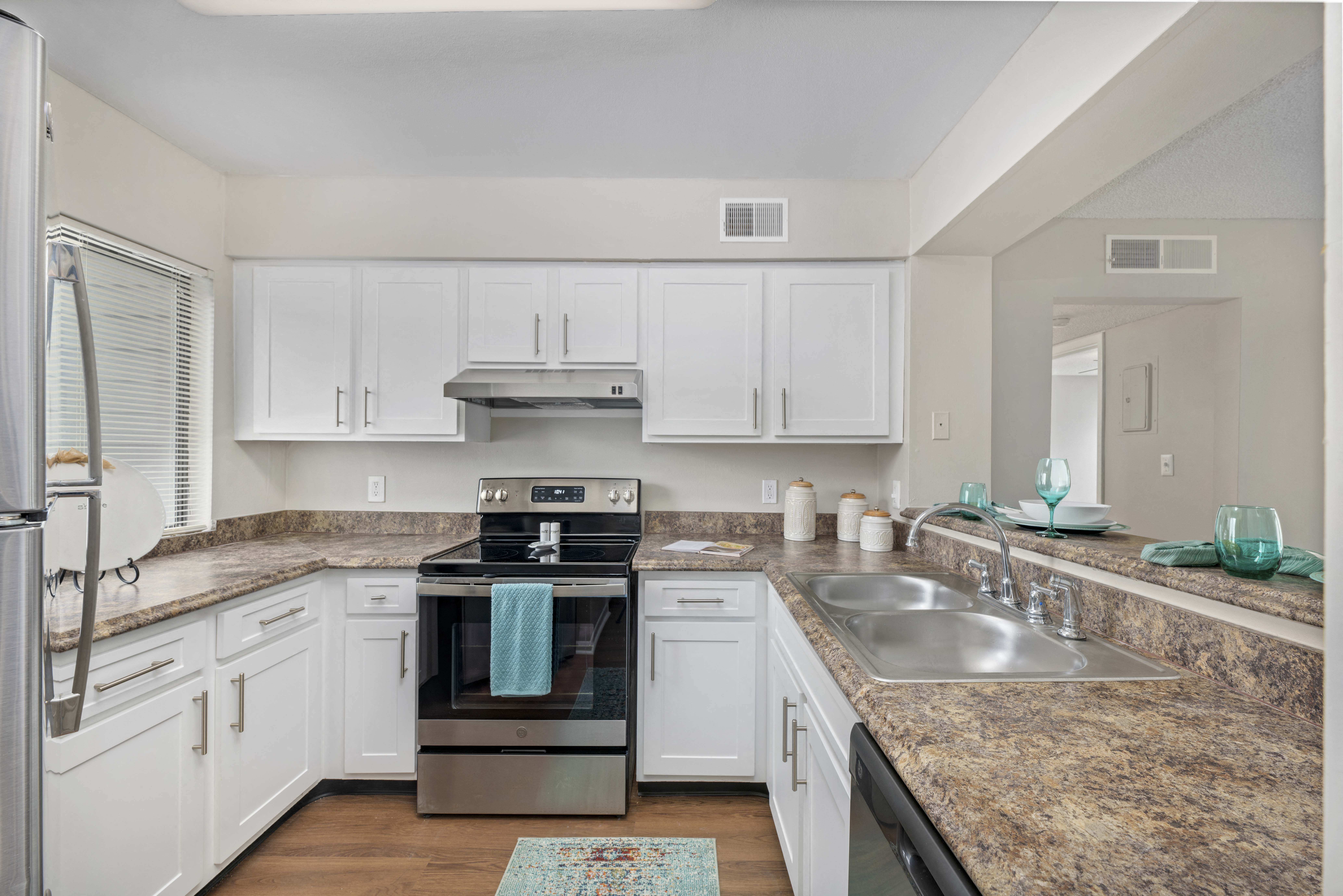 a kitchen with white cabinets and granite counter tops and stainless steel appliances