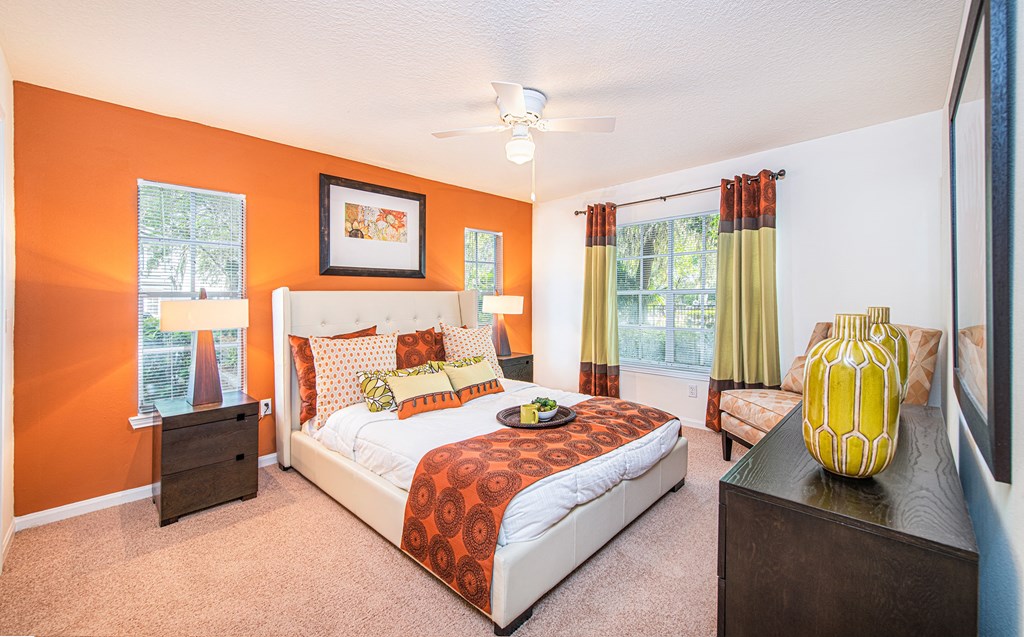 a bedroom with orange walls and a white bed