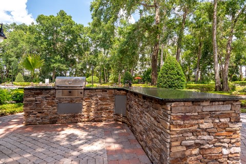 a stone outdoor kitchen with a grill and a stone wall