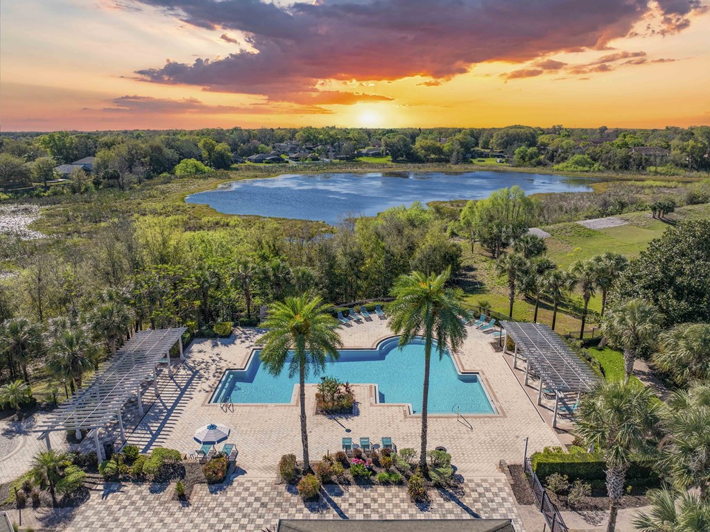 A beautiful sunset view of a pool and a lake from an aerial perspective.