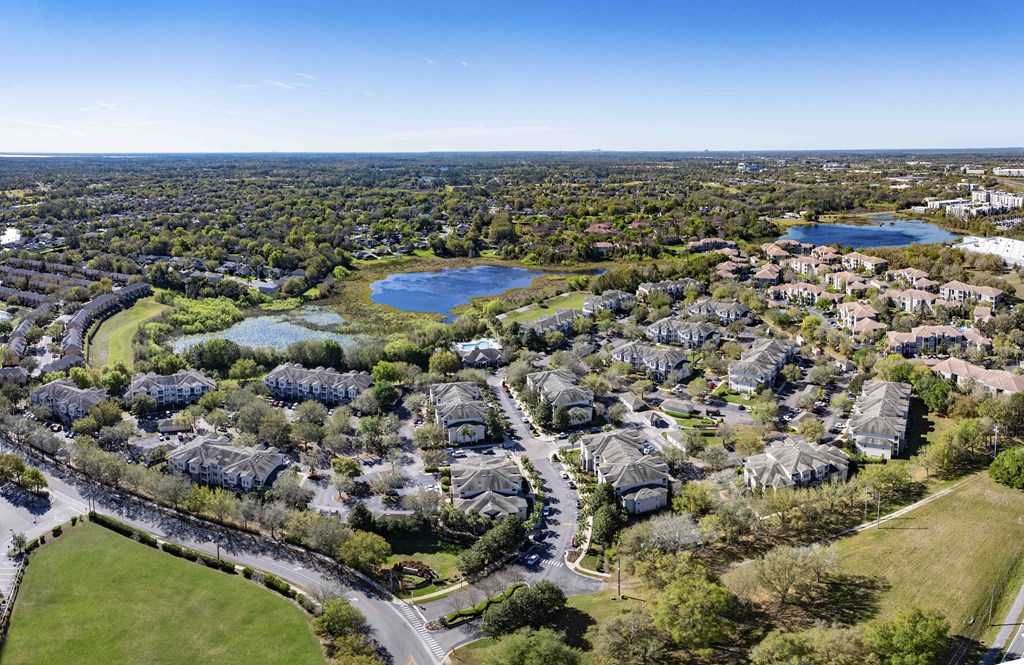 A bird's eye view of a residential area with houses, a lake, and a road.