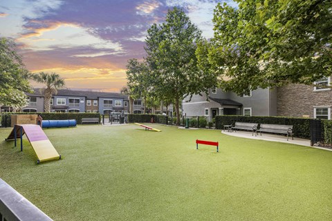 an outdoor play area with benches and a red bench on the grass