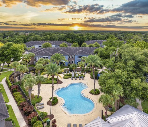 an aerial view of a swimming pool surrounded by trees and buildings