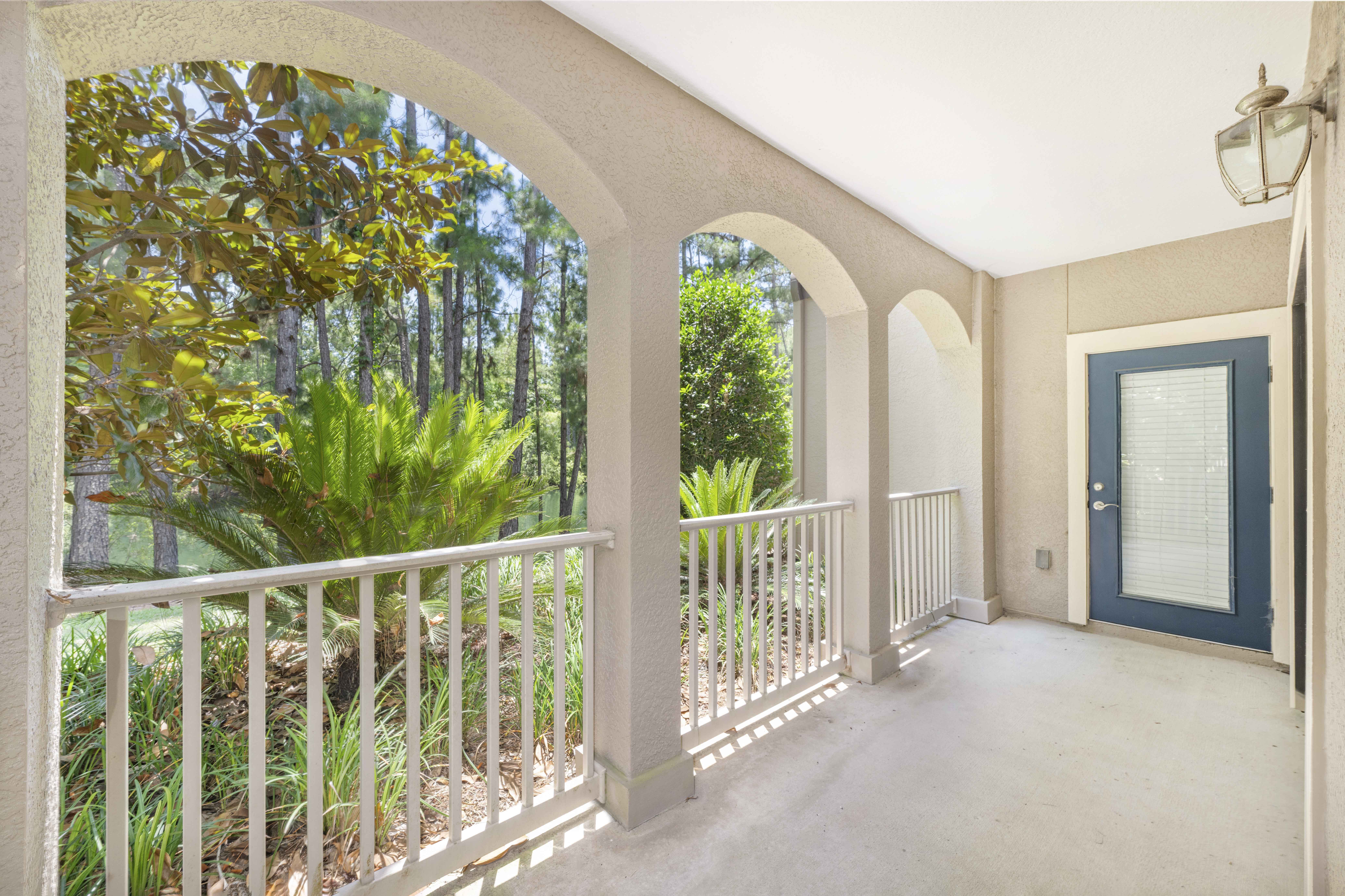 a covered porch with a blue door and a balcony