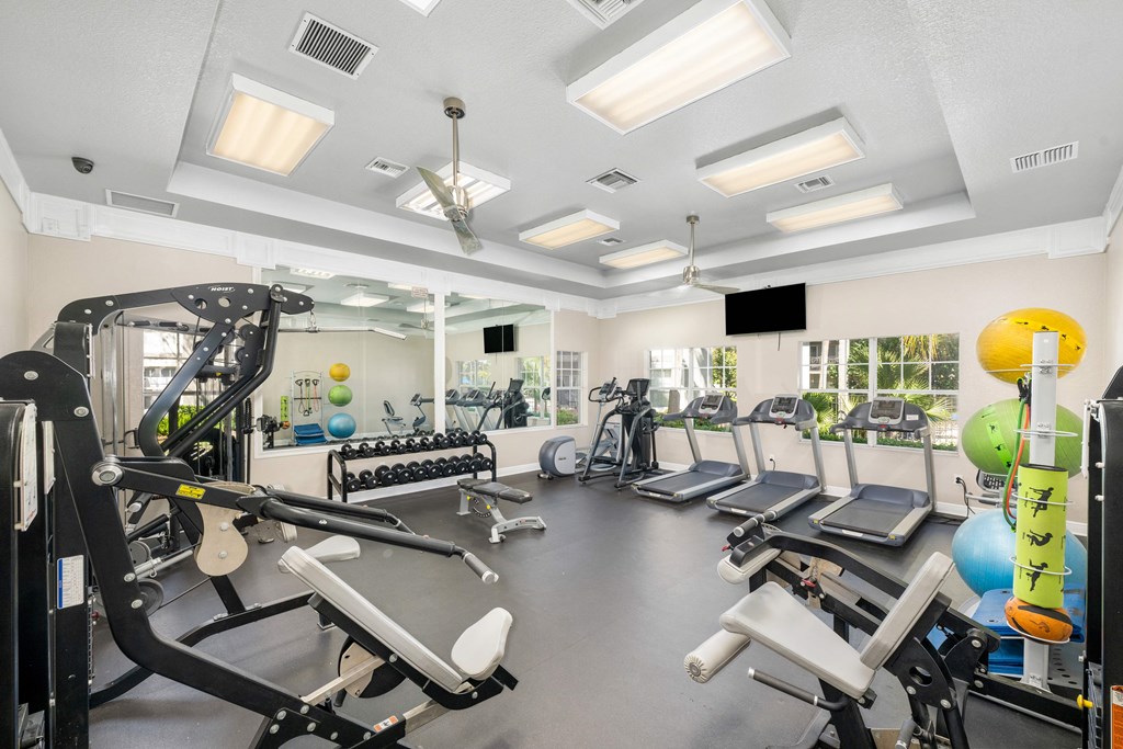 A gym with a variety of equipment including treadmills, weights, and exercise machines.