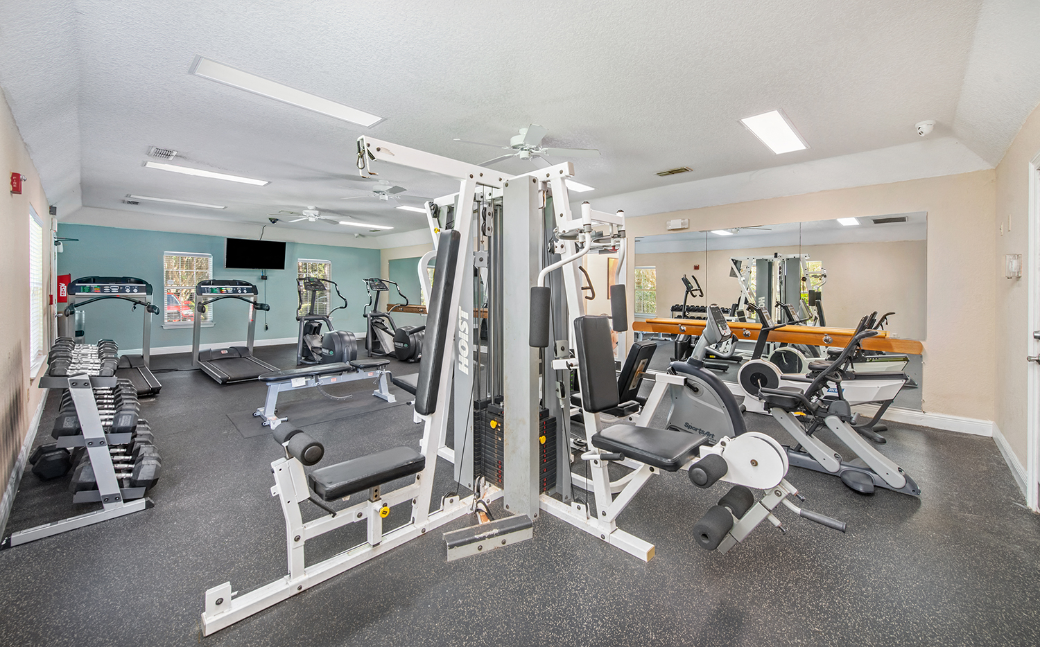 a gym with cardio machines and weights on the floor