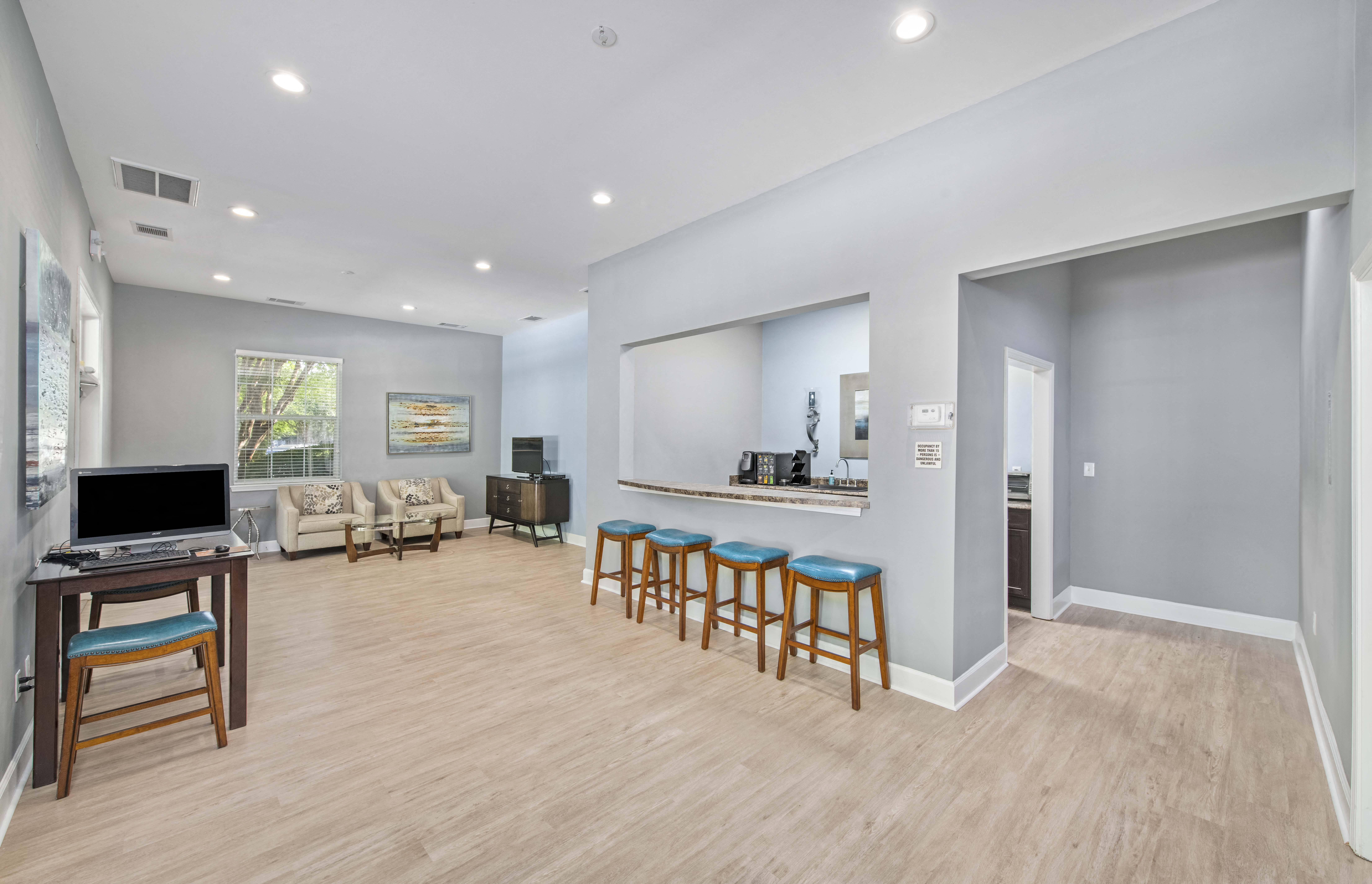 a living room with a couch and a bar with chairs and a television