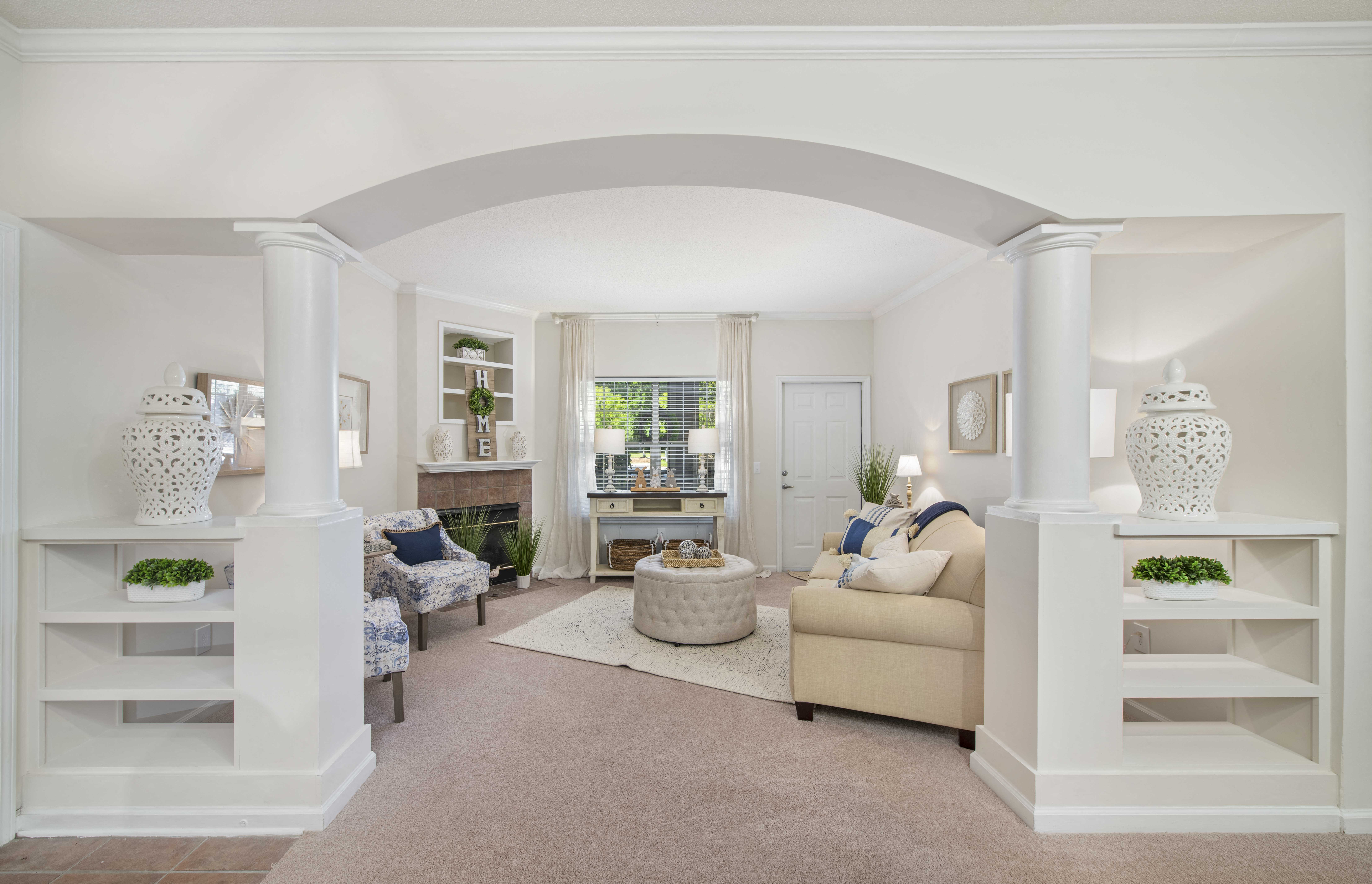a living room with white pillars and a carpet