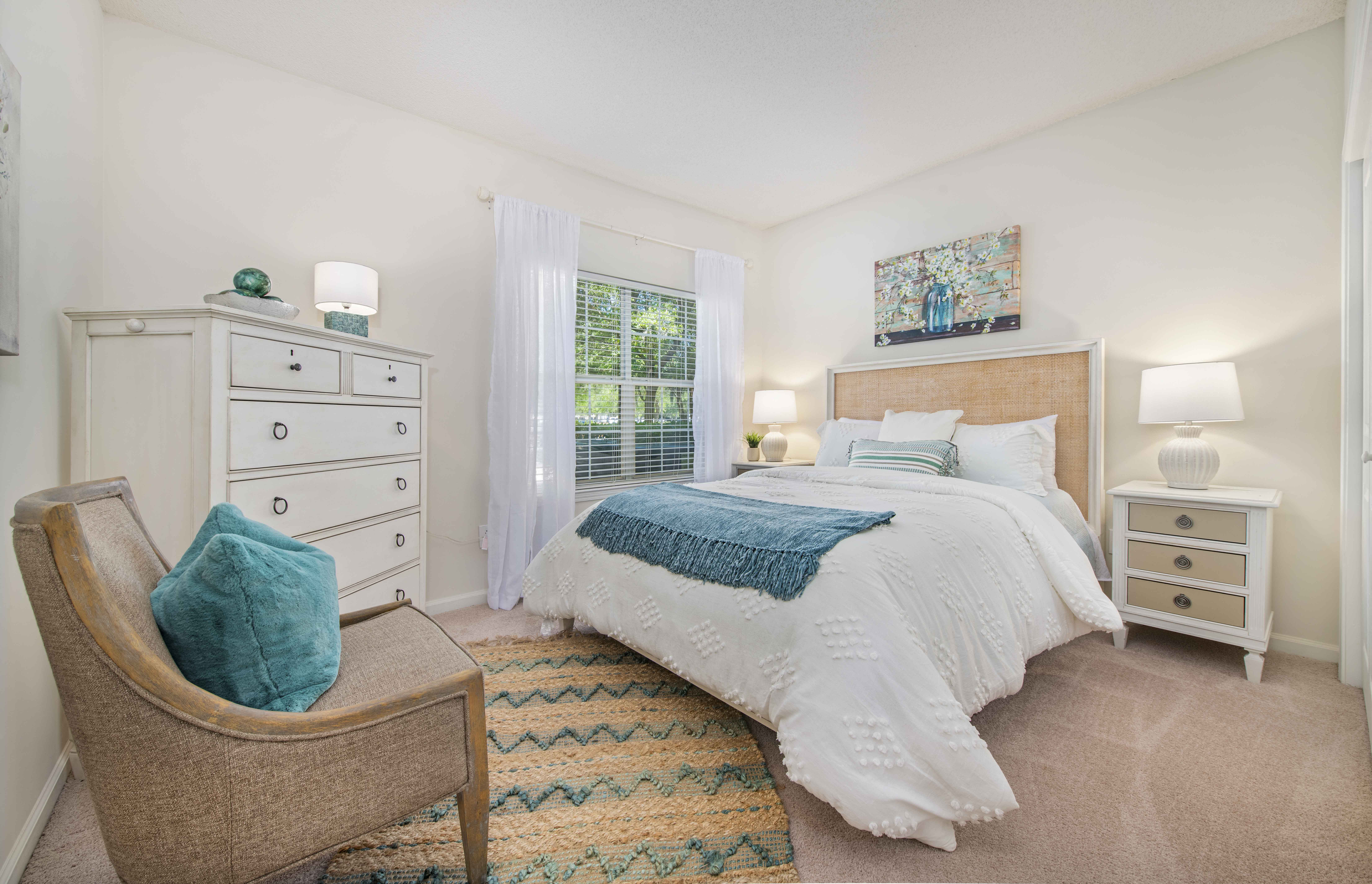 a bedroom with a bed and a chair and a window