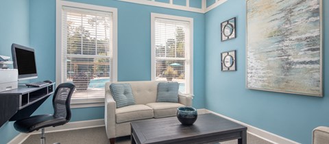 a living room with blue walls and a couch and a desk with a computer