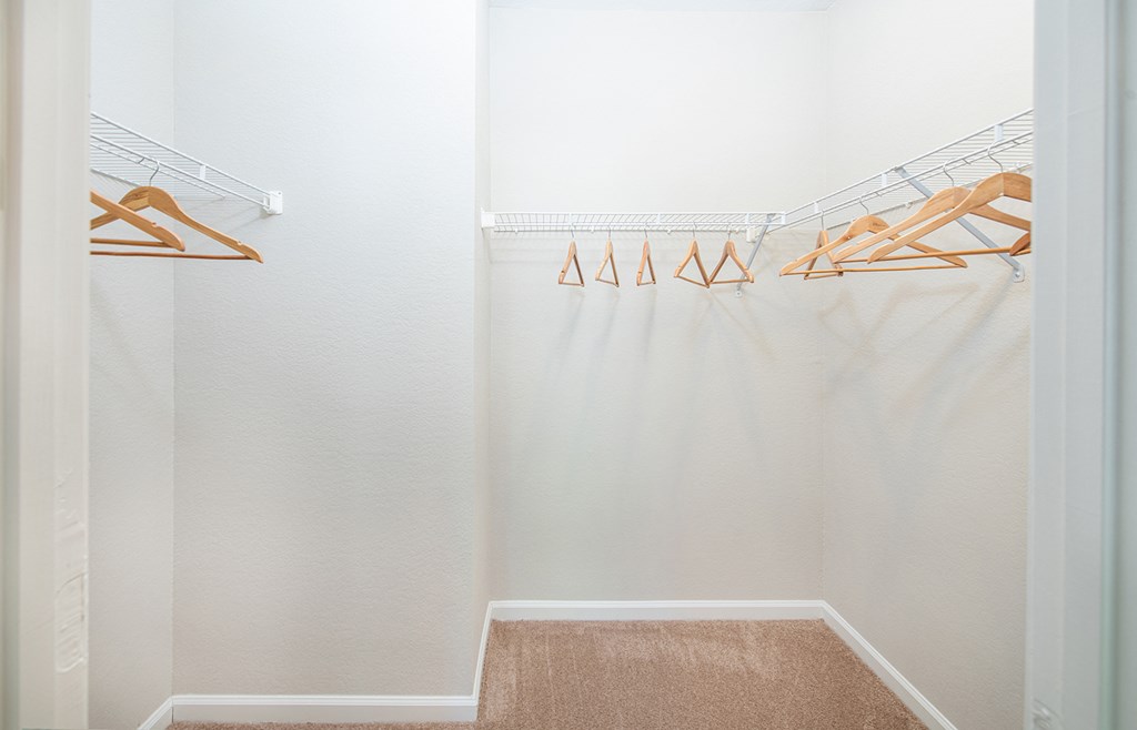 a walk in closet with shoe racks and a white shower curtain