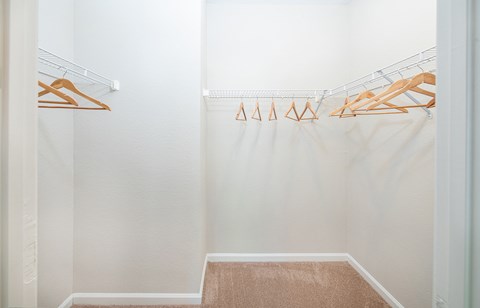 a walk in closet with shoe racks and a white shower curtain