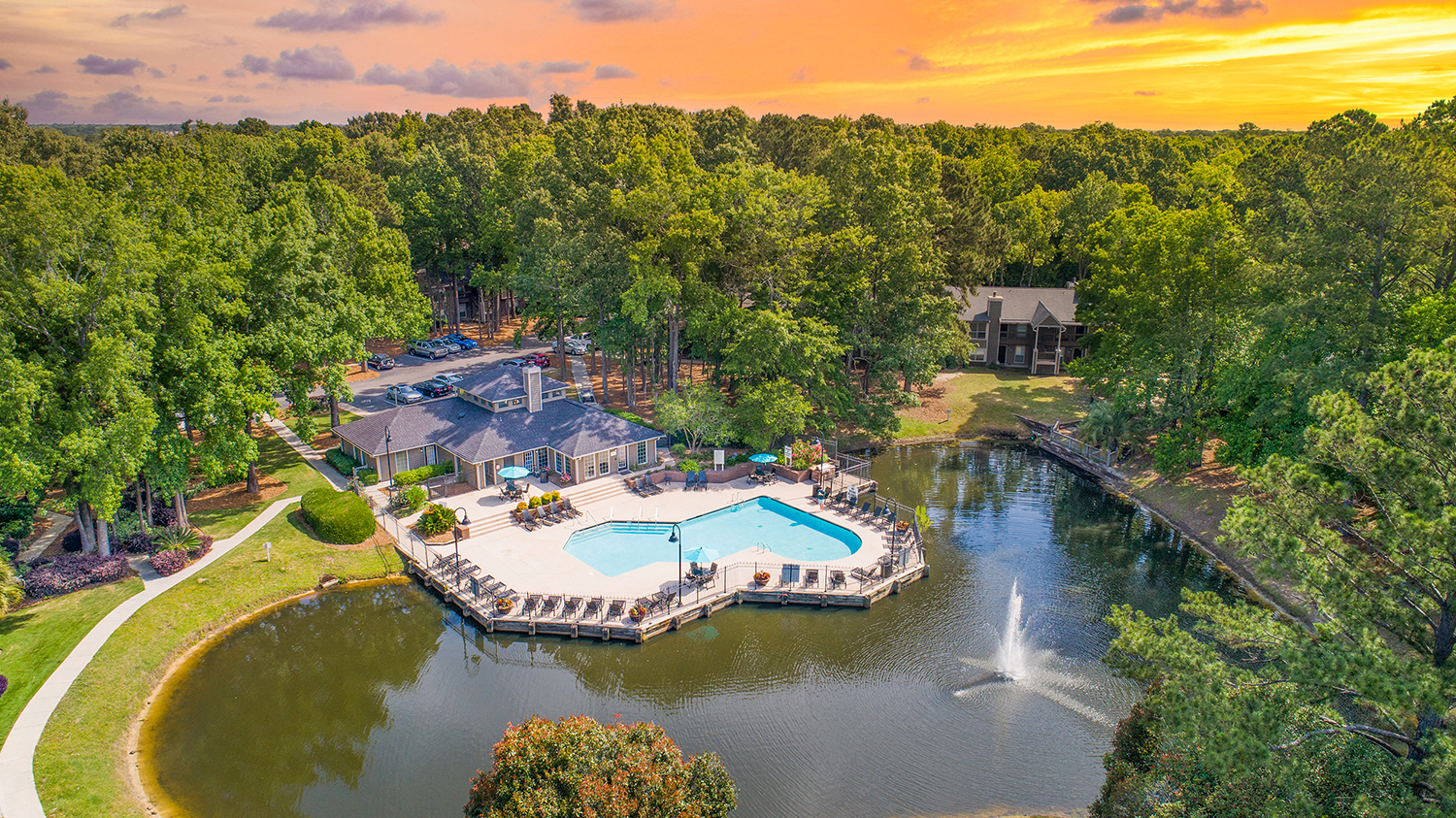 an aerial view of a swimming pool and a lake with a fountain