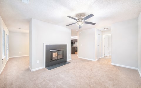 an empty living room with a fireplace and a ceiling fan