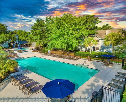 a swimming pool with chairs and umbrellas and a building in the background